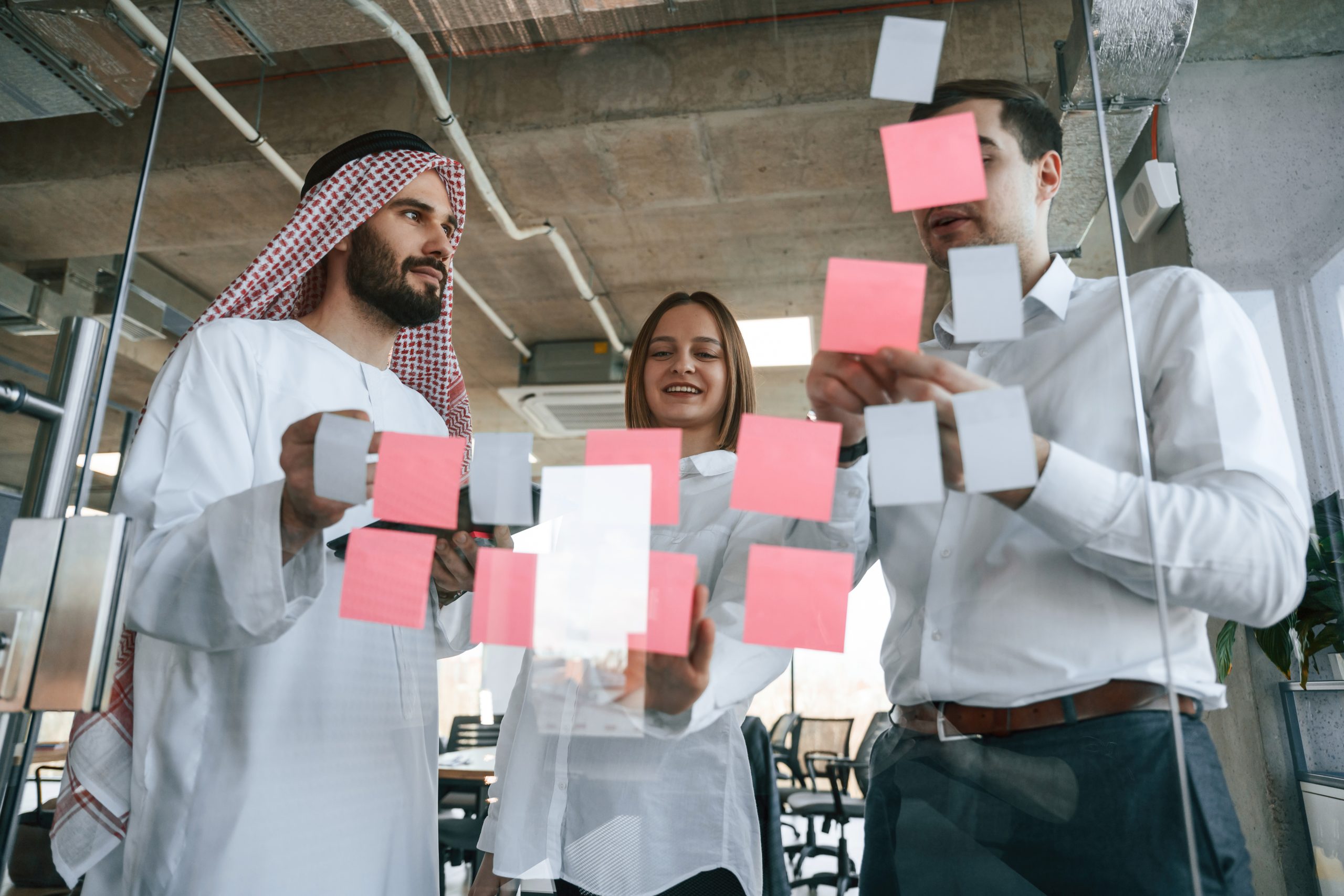 Using stickers on the glass. Muslim businessman in traditional outfit with colleagues in office
